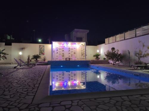 a swimming pool at night with lights on a building at La Casetta in Calimera