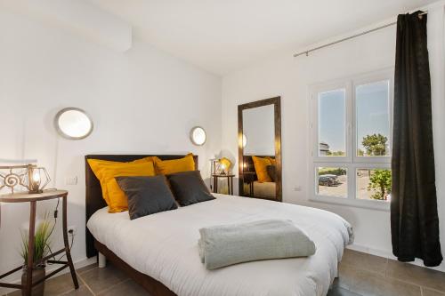 - une chambre avec un grand lit blanc et des oreillers jaunes dans l'établissement Sud coursive naturiste, au Cap d'Agde