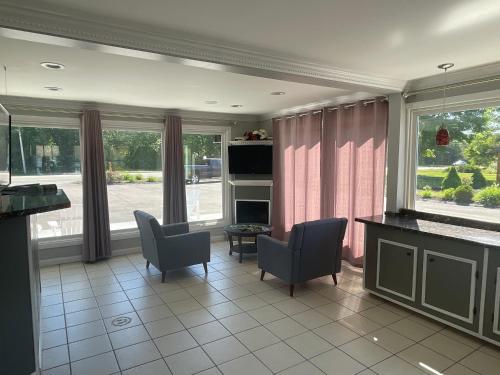 a living room with chairs and a table and windows at Aquastar Inn in Westerly