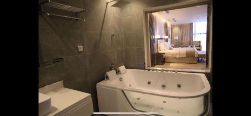 a bathroom with a bath tub and a large mirror at White House Apartments in Khamis Mushayt