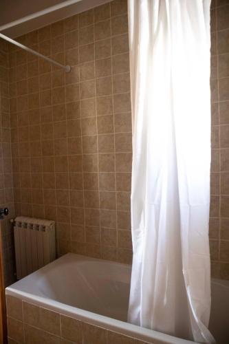a bath tub with a white shower curtain in a bathroom at O Pombal in Alcanena