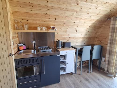 a kitchen with a sink and a counter with chairs at Caledonian Pod. In Caol, Fort William in Caol