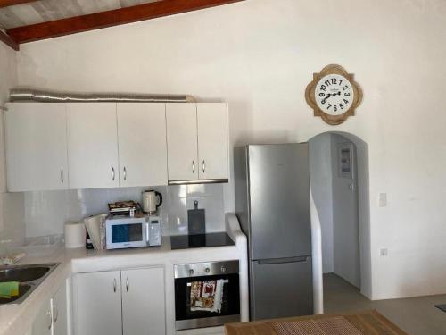 a kitchen with a refrigerator and a clock on the wall at Bianco e Azzuro in Vouliagmeni Lake