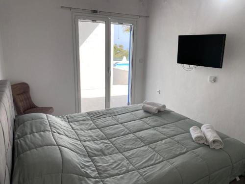 a bedroom with a large bed with a television on the wall at Bianco e Azzuro in Vouliagmeni Lake
