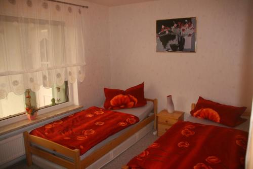 1 dormitorio con 2 camas con sábanas rojas y ventana en Apartment Schinkmann en Bad Frankenhausen