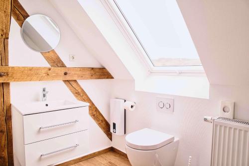 La salle de bains est pourvue de toilettes blanches et d'une lucarne. dans l'établissement Mein Eifel Ferienhaus Altes Pfarrhaus, à Dahlem