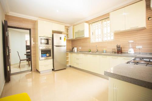 a kitchen with white cabinets and a stainless steel refrigerator at Accra Luxury Homes @ East Legon in Accra