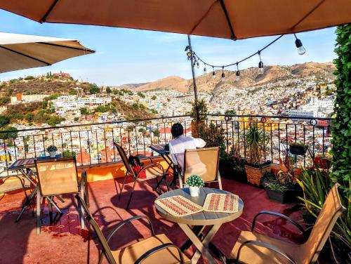 a man sitting at a table on a balcony looking at the city at Casa Rofo in Guanajuato