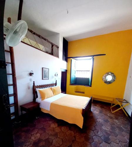 a bedroom with a bed and a yellow wall at Hotel Mision Santa Barbara RNT 4799 in Barichara