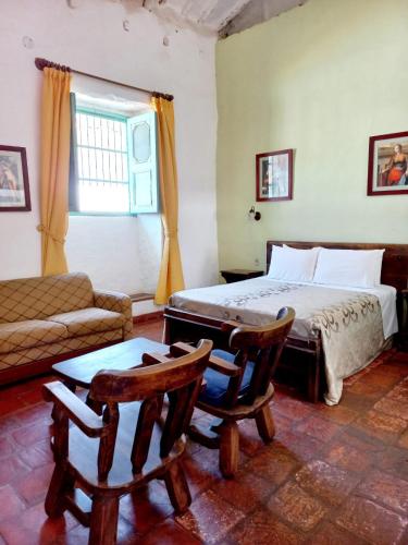 a bedroom with a bed and a couch and a chair at Hotel Mision Santa Barbara RNT 4799 in Barichara