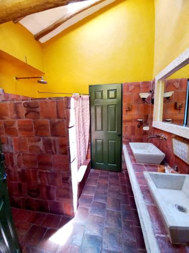 a bathroom with two sinks and a green door at Hotel Mision Santa Barbara RNT 4799 in Barichara