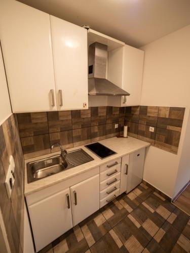 a small kitchen with white cabinets and a sink at Arabeska Majeli in Rukavac