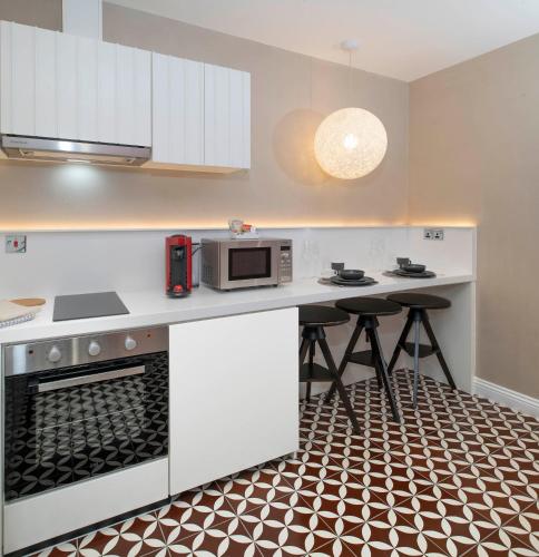 a kitchen with a microwave and a counter with stools at Trueman Court Luxury Serviced Apartments in Liverpool