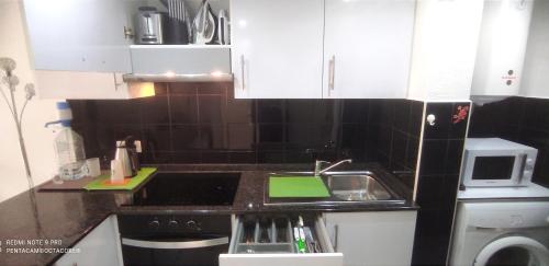 a small kitchen with a sink and a microwave at Castillo Mar 95 in Caleta De Fuste