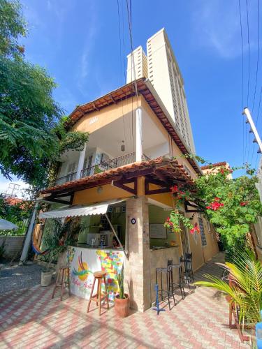 un bâtiment avec des tables et des chaises devant lui dans l'établissement Refugio Hostel Fortaleza, à Fortaleza