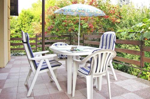 a table and chairs with an umbrella on a patio at Cottage by Lake Dabrowa with Fishing in Wądzyn