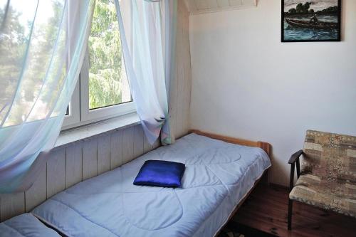a small bed in a room with a window at Cottage by Lake Dabrowa with Fishing in Wądzyn