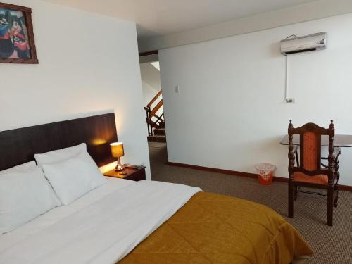 a bedroom with a white bed and a chair at Pukara House in Puno