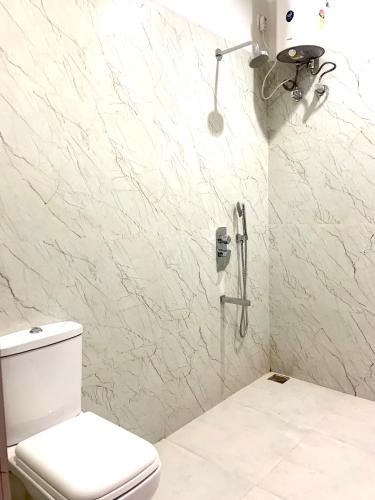 a white bathroom with a toilet and a shower at Hotel Swagatam in Bikaner