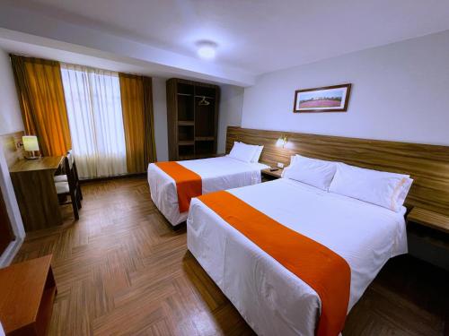 a hotel room with two beds and a desk at Hotel Plaza San Antonio Arequipa in Arequipa