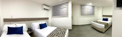 a hotel room with two beds with blue pillows at Seven Inn Hotel in Medellín