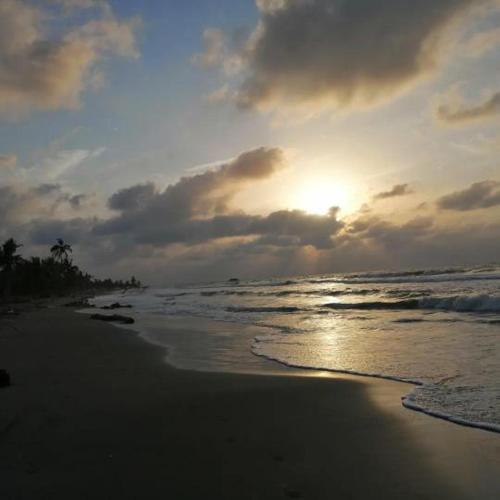 a sunset on a beach with the ocean at LA GAITERA Cabaña in Moñitos