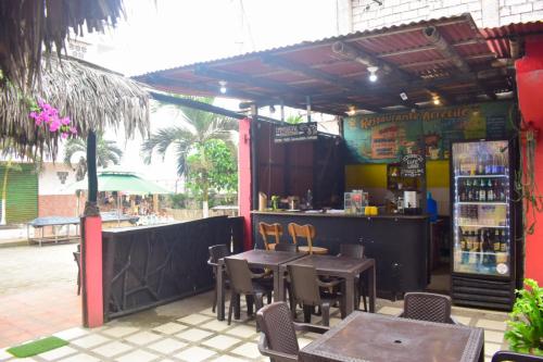 un restaurante con mesas y sillas y un bar en Arrecife Montañita Hostal, en Montañita