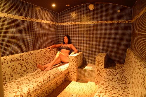 a woman sitting on a bed in a sauna at Camping Les Palmiers in Hyères