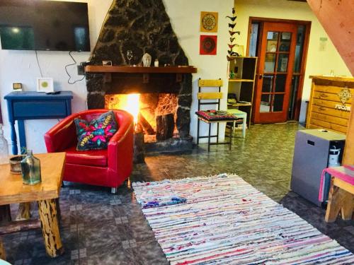 sala de estar con silla roja y chimenea en Hostel Raíz, en Pucón