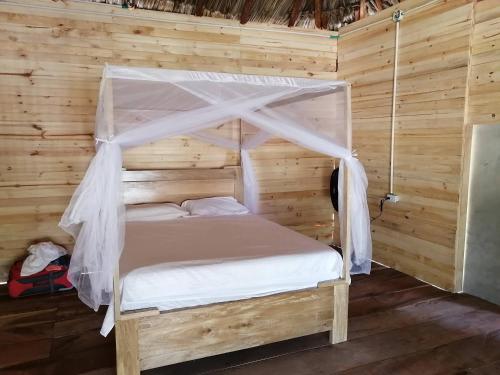 a bed with a canopy in a wooden room at LA GAITERA Cabaña in Moñitos