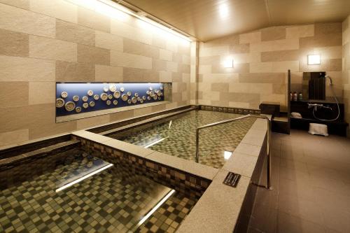 a swimming pool in a hotel room with a tile wall at Hotel Monterey Himeji in Himeji