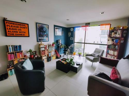 uma sala de estar com um sofá, cadeiras e livros em The Mexican Spot/ 15 min. from Condesa em Cidade do México