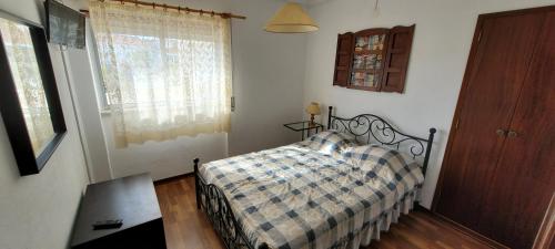 um quarto com uma cama com um cobertor xadrez e uma janela em Alojamentos dos Mangues em São Martinho do Porto