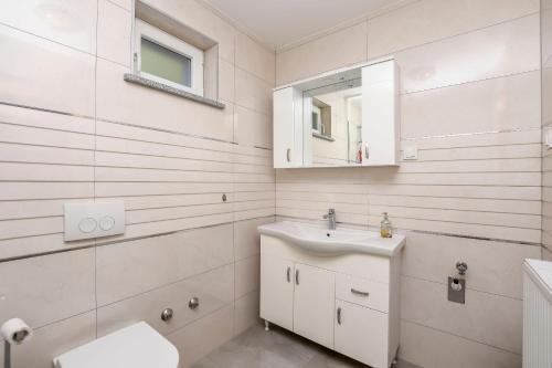Un baño blanco con lavabo y espejo. en Apartments Mario, en Brodarica