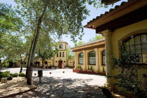 a large yellow building with trees in front of it at Balneario Cervantes in Santa Cruz de Mudela