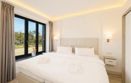 ein weißes Schlafzimmer mit einem großen Bett und einem großen Fenster in der Unterkunft Eden in Binz