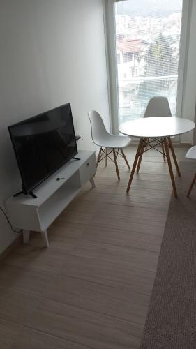 Una sala de estar con televisión, mesa y sillas. en Sunny apartment, en Skopje