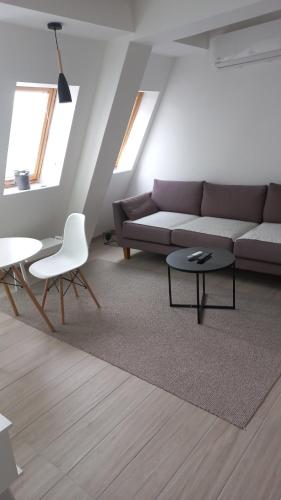 Una sala de estar con un sofá, una mesa y sillas. en Sunny apartment, en Skopje