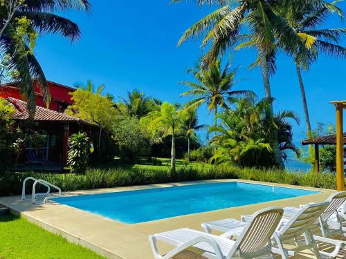 a swimming pool with chairs and a house at Vista Linda Cumuruxatiba in Cumuruxatiba