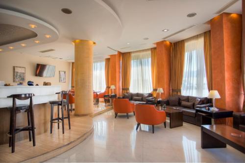 a living room with a couch and tables and chairs at Blue Sea Hotel in Mytilini
