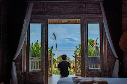 a person standing in a room looking out a door at Gara Gara Sea View in Nusa Penida
