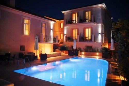a large swimming pool in front of a house at night at Korina Gallery Hotel in Vathi, Ithaka