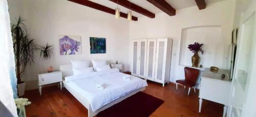 a white bedroom with a white bed and a chair at Casa din colțul Cetății in Hărman