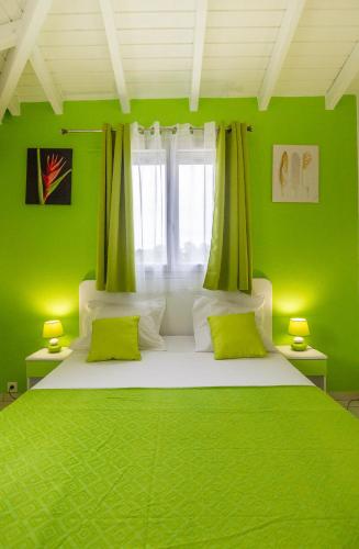 a green bedroom with a large bed with green walls at Les Villas de Boisvin in Le Moule