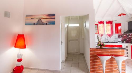 a kitchen with white walls and a red lamp at Les Villas de Boisvin in Le Moule