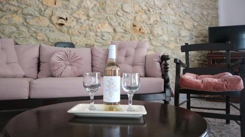 a bottle of wine and two wine glasses on a table at Artemis House in Agios Nikolaos