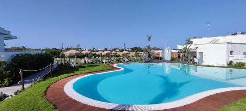 una piscina in un resort con sedie e tavoli di Samanà Bed and Breakfast a Punta Prosciutto