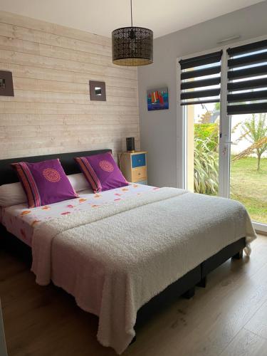 een slaapkamer met een groot bed met paarse kussens bij Maison d'Hôtes La Marie Pierre in Pluherlin