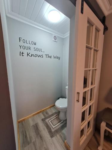 a bathroom with a toilet and a sign on the wall at Oorgenoeg in Langebaan in Langebaan