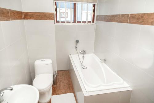 a white bathroom with a toilet and a bath tub at Grayville Apartments in Lusaka
